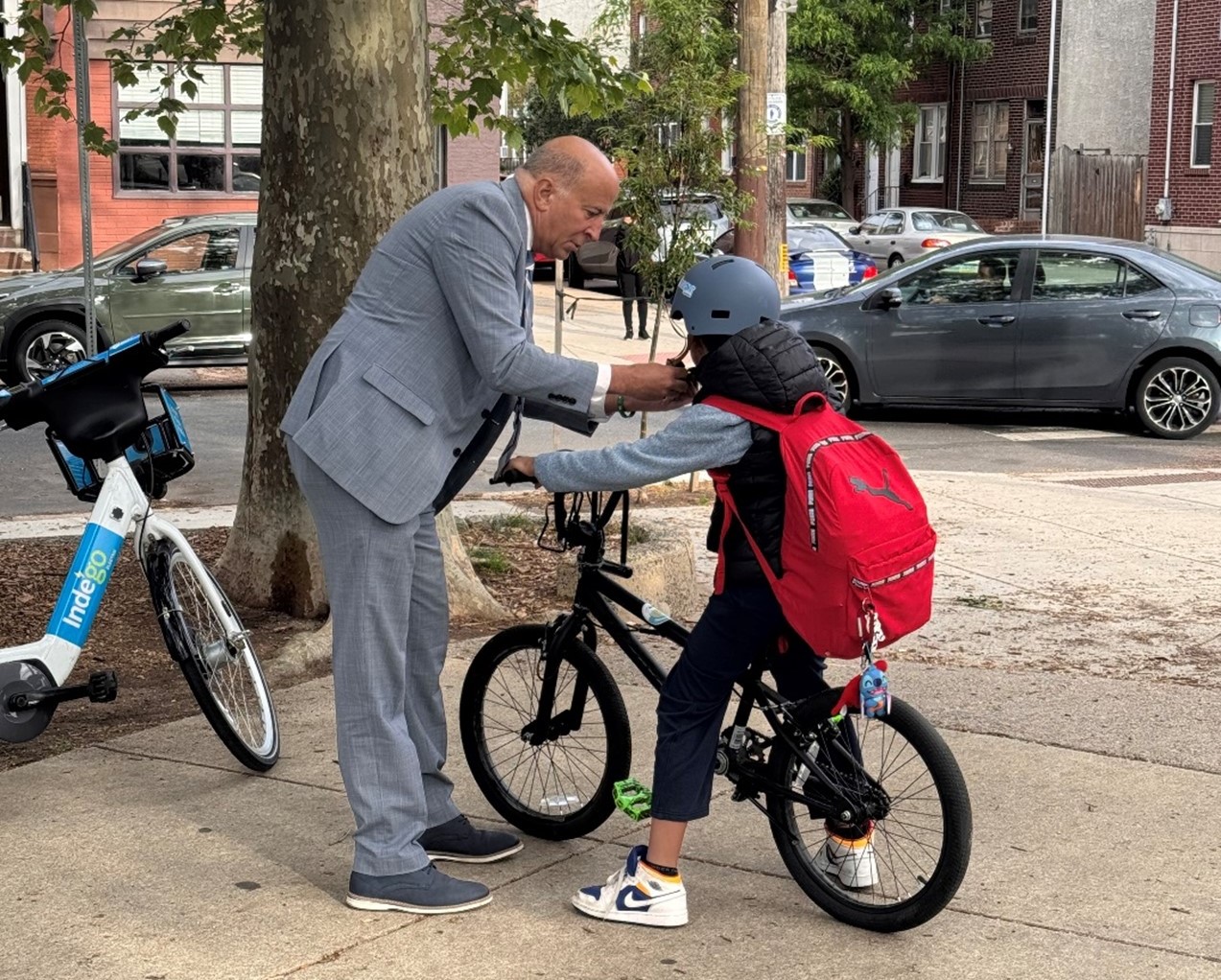 CM Squilla giving helmet to a student on a bicycle.